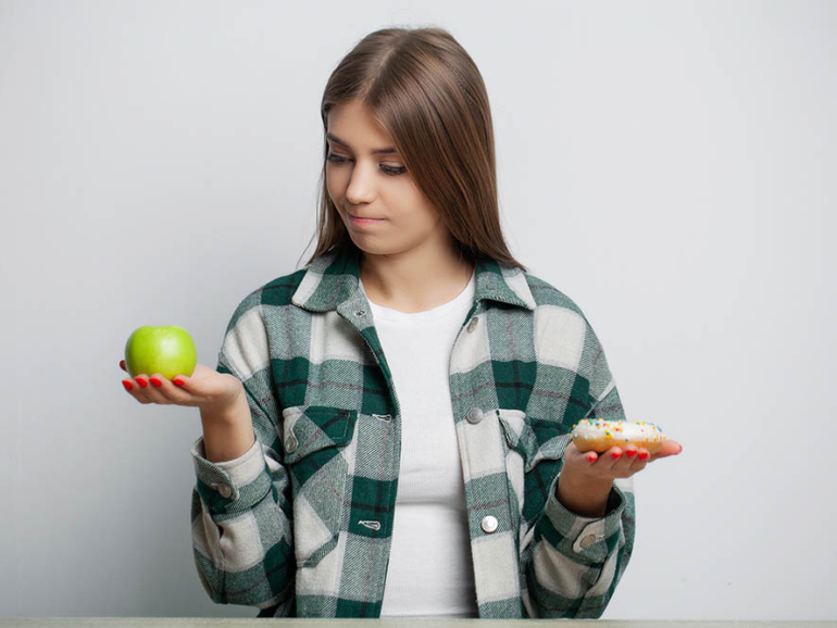 Cute woman makes a choice between healthy and harmful food.